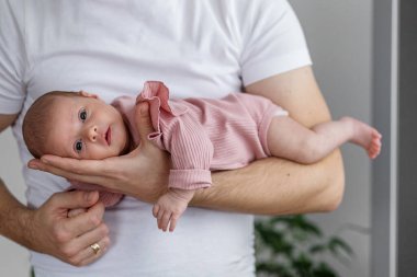 Pembe giyinmiş yeni doğmuş bir bebek bir erkeğin kollarında rahat bir şekilde yatar. Ev ortamında özenle ve sevgiyle desteklenir. Ağaçtaki kaplan.
