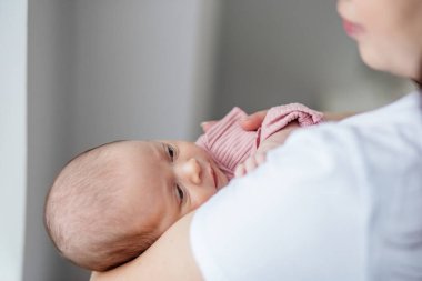 Nazik bir an, yeni doğmuş bebeğini kucağında tutan bir anneyi yakalar. Atmosfer yumuşak ışıklandırmayla huzurlu, aralarındaki bağı vurguluyor. Bebek sakince bakar, rahat bir elbiseye sarınır..