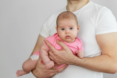 Pembe tulumlu, tetikte bir bebeği tutan bir adamın yakın plan fotoğrafı. Bakım, bağlanma ve koruyucu babalık gösteriyor..