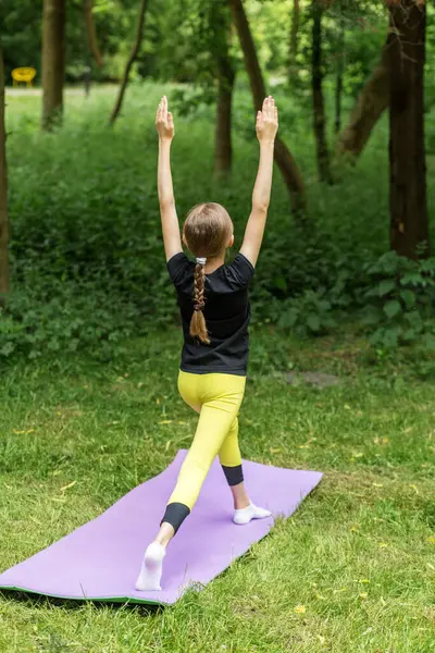 Ergen bir çocuk açık hava ortamında paspasın üzerinde yoga pozu veriyor. Egzersiz dengeyi, farkındalığı ve fiziksel uygunluğu, konsantrasyonu ve hareketi teşvik eder..