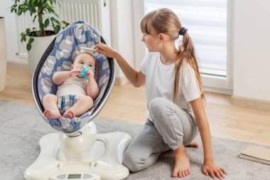 Bakıcı ablası yerde yatarken küçük kardeşlerinin başını okşuyor. Huzurlu, şefkatli bir anı paylaşıyor..