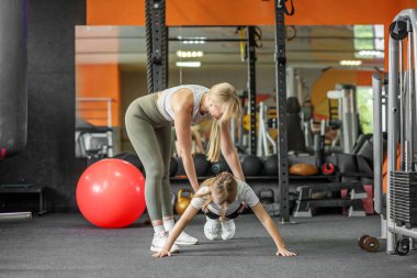 Değer veren bir anne modern spor salonunda kızına destek oluyor, gücü, disiplini ve sağlıklı bir yaşam tarzını teşvik ediyor..