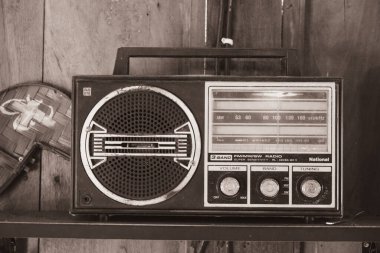 Eski bir 3 bantlı transistör radyo ahşap bir dolabın üstünde duruyor..