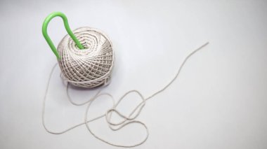 Bir makara beyaz polyester örgü ipliği ve örgü iğnesi. Beyaz bir arkaplanda fotoğraflandı.