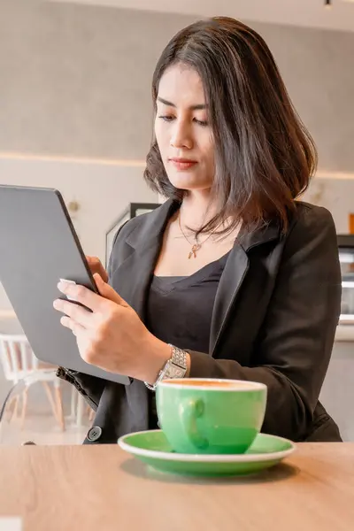 Siyah spor ceket giyen güzel bir kariyer kadını bir kafede tablet tutuyor..