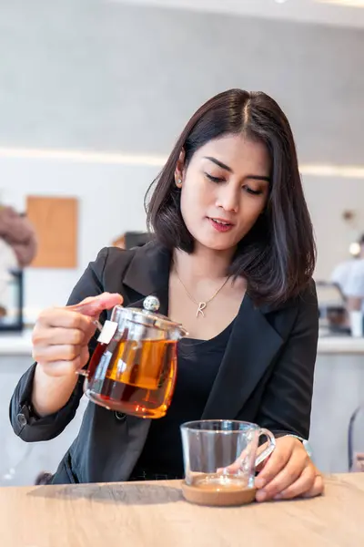 Siyah takım elbiseli güzel bir kadın fincana çay döküyordu..