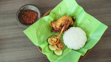 Kızarmış ördek, beyaz pirinç, dilimlenmiş domates ve salatalık ve yeşil çizgili tabakta servis edilen baharatlı sambal sosunun yer aldığı geleneksel Endonezya yemeği..