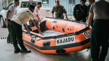 Bir ekip garajda içinde araçlar olan turuncu şişme bir kurtarma botu hazırlıyor. Acil durum müdahalelerine hazır olduklarını gösteriyorlar..