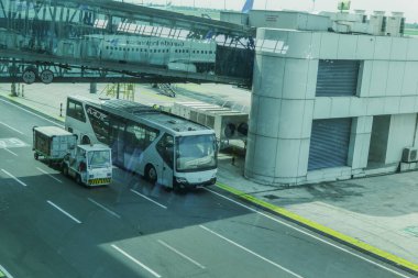 Otobüsler ve havaalanı bagaj taşıyıcıları Soekarno-Hatta Havaalanı, Jakarta 'nın 3. terminalinin jet köprüsünün altından geçiyorlar..