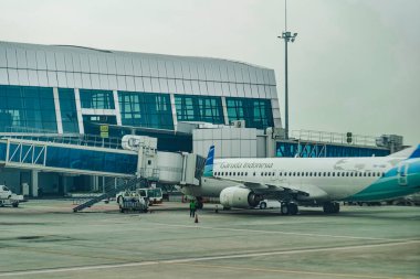 Bir Garuda Endonezya uçağı G64 kapısında park halinde, yer ekibi kargo ve bakım faaliyetleriyle ilgileniyor..