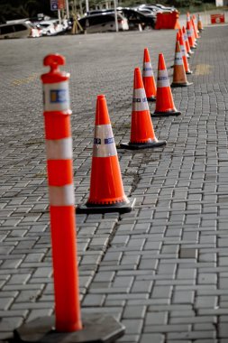 Geceleri kaldırımlı bir yolda turuncu trafik konileri. Şehir ışıklarıyla aydınlatılıyor. Güvenliği ve yönü sağlıyorlar..