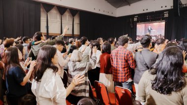 A vibrant Christmas service at Mawar Sharon Church with attendees raising their hands in worship, symbolizing their acceptance of Jesus as their savior. clipart