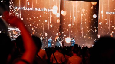 Bir grup sanatçı ve koro üyesi Noel 'i sahnede ışıltılı bir Noel ağacı ve 