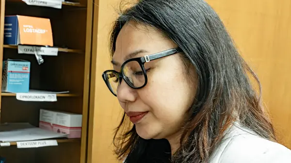 Kadın bir doktor ilaç dolu ahşap bir dolabın önünde duruyor..