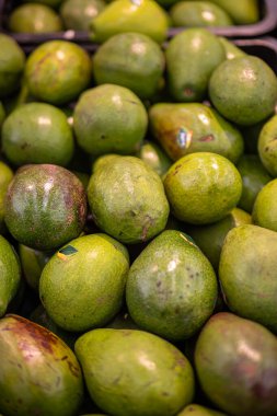 Markette canlı bir yeşil avokado gösterisi, pürüzsüz dokularını ve zengin renklerini sergiliyor, sağlıklı yemekler, guacamole ve besleyici atıştırmalıklar için ideal..
