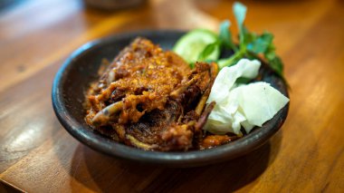 Kızarmış ördek, beyaz pirinç, dilimlenmiş domates ve salatalık ve taş bir tabakta servis edilen baharatlı sambal sosundan oluşan geleneksel bir Endonezya yemeği..