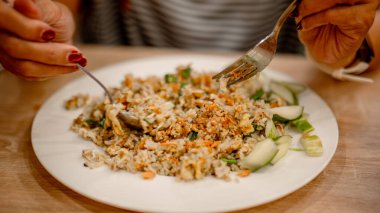 Kızarmış pirinç Endonezya 'daki en popüler yemektir. Bu fotoğrafta bir kadın çatal ve kaşıkla kızarmış pirinç yiyor..