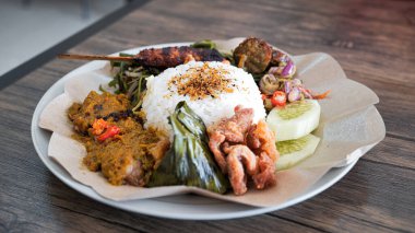 Nasi Bali, içinde pirinç, soya sosu domuz eti, kızarmış domuz derisi, domuz derisi ve kırmızı soğan soslu papaya çiçeği sebzeleri bulunan tipik bir Bali yemeği..