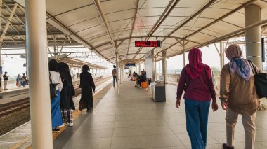 Passengers wait for the commuter line train at Manggarai Station, with the backdrop of the metropolitan city of Jakarta. clipart