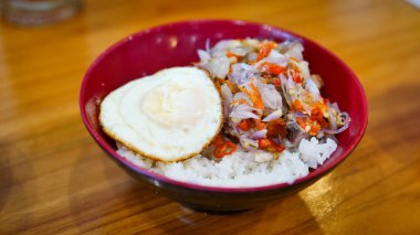 Mükemmel kızarmış yumurta, baharatlı kırmızı biber, arpacık soğanı ve lezzetli et içeren canlı bir pirinç kasesi. Her yemek için görsel olarak çekici, iştah açıcı bir yemek..