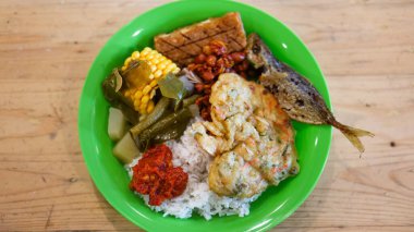 Bu öğle yemeğinin menüsünde pirinç var. Kızarmış balık, tofu, tempeh ve sebze var. Mısır ve sambal da dahil..