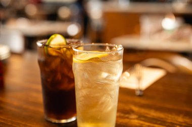 Bir bardak soğuk limon çayı ve üzerinde portakal dilimleri olan limonata..