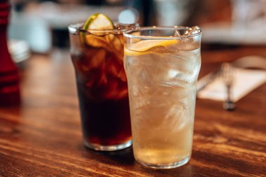 Bir bardak soğuk limon çayı ve üzerinde portakal dilimleri olan limonata..