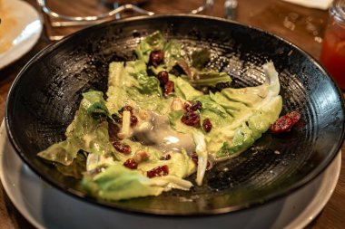 İçinde salata artıkları olan siyah bir tabak..