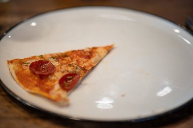 Beyaz seramik tabakta bir dilim pizza..