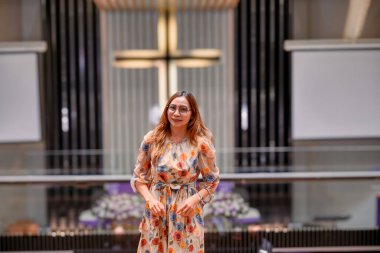 Omuz hizasında sarı saçlı güzel bir kadın kilisedeydi. Duvarda bir haç var..