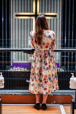 Omuz hizasında sarı saçlı güzel bir kadın kilisedeydi. Duvarda bir haç var..