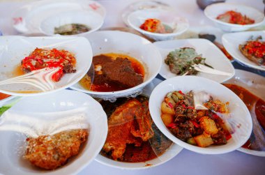 Bir restoran masasında küçük tabaklarda servis edilen çeşitli Padang spesiyaliteleri. Ve ziyaretçiler istediklerini doğrudan alabilirler..
