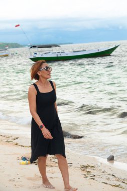 Omuz hizasında sarı saçlı ve güneş gözlüklü çok güzel bir kadın sahilde bir öğleden sonranın tadını çıkarıyordu. Güzel beyaz kumlarla sahil boyunca yürüyorum.