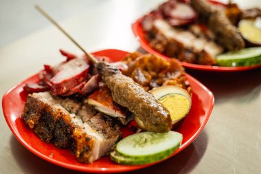 Bir Çin restoranının menüsü domuz eti, domuz eti siu, sosis, domuz kulağı, deri, yumurta ve domuz satayından oluşur. Salatalık dilimleriyle.