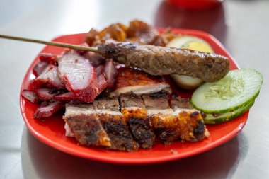 Bir Çin restoranının menüsü domuz eti, domuz eti siu, sosis, domuz kulağı, deri, yumurta ve domuz satayından oluşur. Salatalık dilimleriyle.