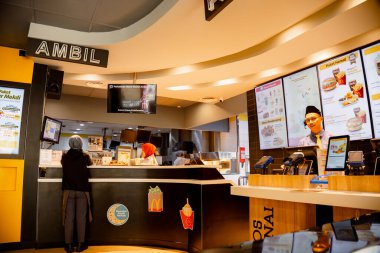 Fast food restoranı müşterilere servis yapıyor. Sağda siparişin verileceği yer, solda ise ambil kelimesinin geçtiği yer..