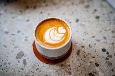 Yüzeyinde latte sanat olan bir fincan kahve, yapraklar ve kalpler oluşturur.. 