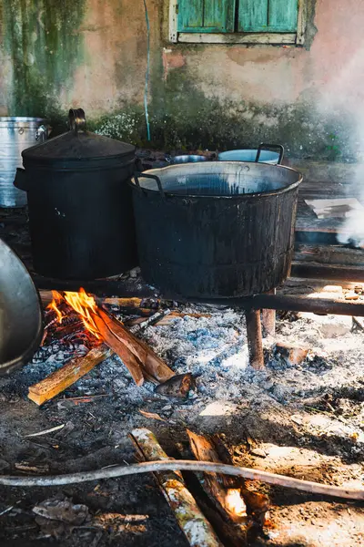 Büyük, yanmış görünümlü bir kazan yakacak odunla yemek pişirmek için kullanılıyor. Duman sobayı doldurur, güneş ışığıyla aydınlatır..