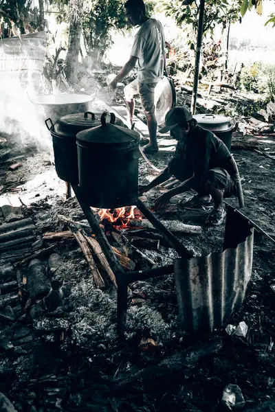 Beline palayla bağlanmış yaşlı bir adam yakacak odun yakıyor. Kazan kullanarak yemek pişirmek için kullanılacak..