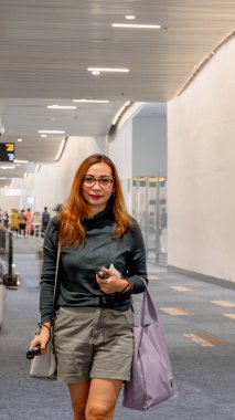 Güzel bir kadın, Sukarno-Hatta havaalanı, Jakarta 'daki varış terminalinin koridorunda yürüyor..