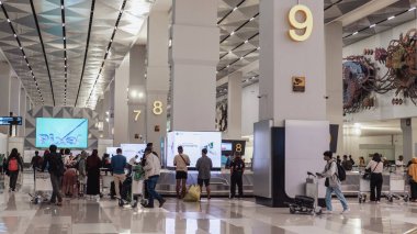 Gelen terminalde bagajlarını geri almak için bekleyen yeni inen yolcular..