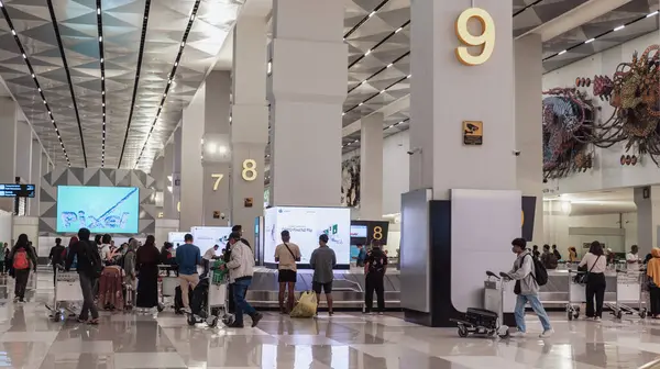 Gelen terminalde bagajlarını geri almak için bekleyen yeni inen yolcular..