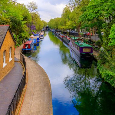 Kanal dar botlar veya mavnalar baharda yürüyüş yolunun yanında çiçek açan ağaçlar ve suya yansıyan mavi gökyüzü ile birlikte Little Venice, Paddinton, Londra 'da diziliyorlar. Yüksek kalite fotoğraf