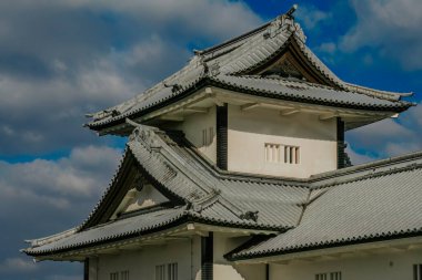 Kanazawa Kalesi 'nin görüşü, Japonya' nın feodal tarihinin ve kültürel mirasının bir sembolü. Kale beyaz alçıdan duvarlar ve çok katmanlı, kurşun kiremitli çatılar açık mavi bir gökyüzüne karşı duruyor. Şıklığın