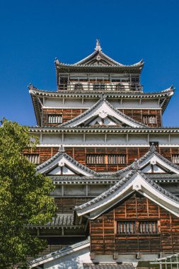 Hiroşima, Japonya - 6 Mart 2018 - Hiroşima Şatosu, atom bombasından sonra 1950 'lerde yeniden inşa edildi, çok katmanlı ahşap ve beyaz cephe, geleneksel fayanslı çatılar ve detaylar içerir. Üst katları bir kleanın altında göster