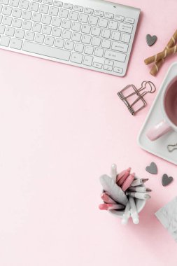 Feminen bir kadın çalışma alanı. Bilgisayarın gümüş klavyesi ve pastel pembe arka planda fotokopi alanı var. Mum ve diğer ofis alanı ve masaüstü beyaz kırtasiyeli resim