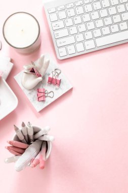 Feminen bir kadın çalışma alanı. Bilgisayarın gümüş klavyesi ve pastel pembe arka planda fotokopi alanı var. Mum ve diğer ofis alanı ve masaüstü beyaz kırtasiyeli resim