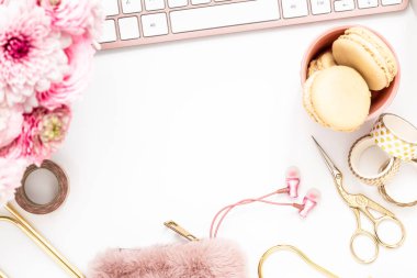 A femininely styled desktop in shades in gold and dusty pink with modem stationery. Lifestyle theme inspired by the office workspace of a stylish woman. Flat lay with fresh flowers pink keyboard and