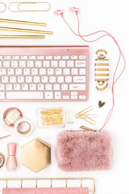 A femininely styled desktop in shades in gold and dusty pink with modem stationery. Lifestyle theme inspired by the office workspace of a stylish woman. Flat lay with fresh flowers pink keyboard and