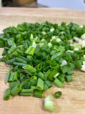 Doğranmış yeşil soğanlar, masanın üzerindeki tahta kesme tahtasının üzerinde. Mutfakta, yemek, yemek, yemek.